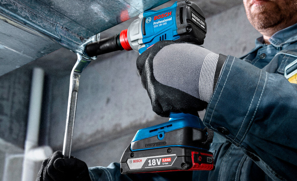 Klucz udarowy BOSCH Professional GDX 18V-285 06019N2122 plac budowy osoba dokręca śruby na metalowej konstrukcji do szybkiego i skutecznego dokręcania oraz odkręcania śrub i nakrętek wysoki moment obrotowy mechanizm udarowy eliminuje konieczność stosowania dźwigni lub dużej siły fizycznej