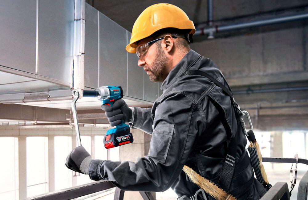 Klucz udarowy BOSCH Professional GDS 18V-350 06019M5021 plac budowy osoba dokręca śrubę na metalowej konstrukcji dla majsterkowiczów wszechstronne zastosowanie wydajność