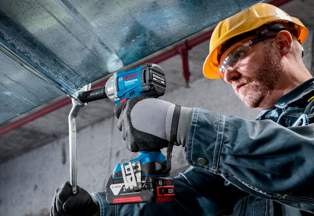 Klucz udarowy BOSCH Professional GDS 18V-350 06019M5021 plac budowy osoba dokręca śruby na metalowej konstrukcji regulacja prędkości obrotowej na spuście (od 0 do 2300 obr/min) obroty prawo/lewo obroty w prawo umożliwiają wkręcenie śruby lub dokręcenie nakrętki obroty w lewo odpowiadają za odkręcenie nakrętki lub wykręcenie śruby