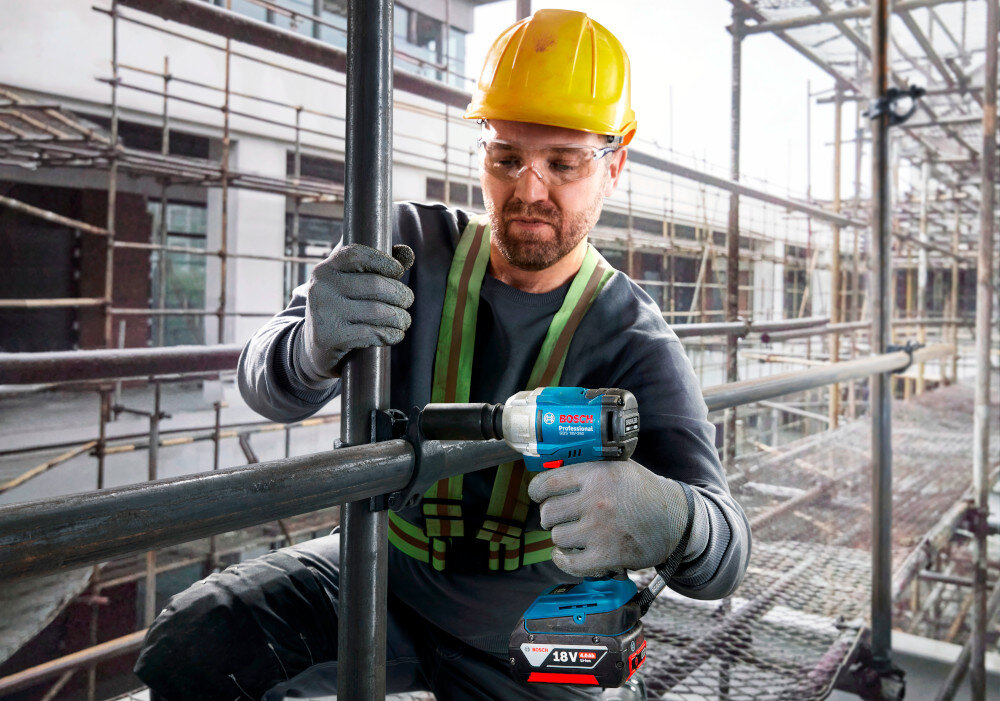 Klucz udarowy BOSCH Professional GDS 18V-350 06019M5021 plac budowy osoba dokręca śruby na metalowej konstrukcji uchwyt narzędziowy oparty na pierścieniu ciernym 1/2 cala z napędem kwadratowym otworze przelotowym sprawnej pracy pierścień cierny stabilnie utrzymuje nasadkę podczas pracy otwór przelotowy pozwala na zastosowanie dodatkowego zabezpieczenia do intensywnych zastosowań montażowych i serwisowych kompatybilność z popularnym osprzętem 1/2 cala