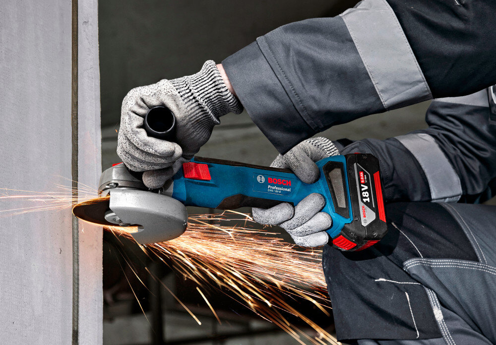 Szlifierka kątowa BOSCH Professional GWS 18V-8 06019N9001 osoba trzyma szlifierkę w dłoniach tnie metalową rurkę profesjonalna renomowana firma BOSCH solidne narzędzie do obróbki materiałów wysoka moc wydajność do cięcia szlifowania polerowania