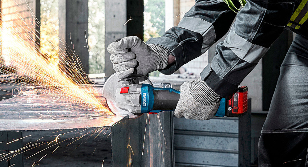 Szlifierka kątowa BOSCH Professional GWS 18V-8 06019N9001 osoba trzyma szlifierkę w dłoniach tnie metalowy element bezpieczeństwo użytkowania restart Protection wbudowany system zapobiegania przypadkowemu włączeniu po zaniku prądu ochrona przed przeciążeniem wyłącznik przeciążeniowy Overload Protection ochrona narzędzia przed przegrzaniem