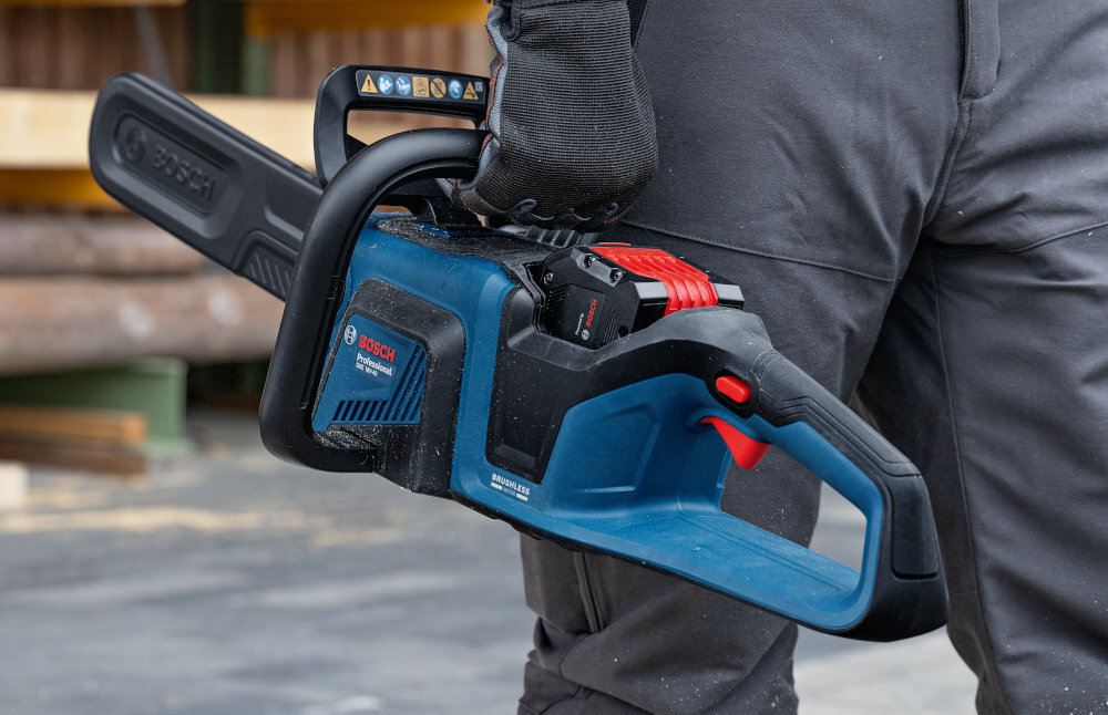 Piła akumulatorowa BOSCH Professional GKE 18V-40 06008D3000 plac budowy osoba niesie piłę w dłoni szybkie i precyzyjne cięcie drewna, belek i grubych gałęzi akumulatorowy napęd