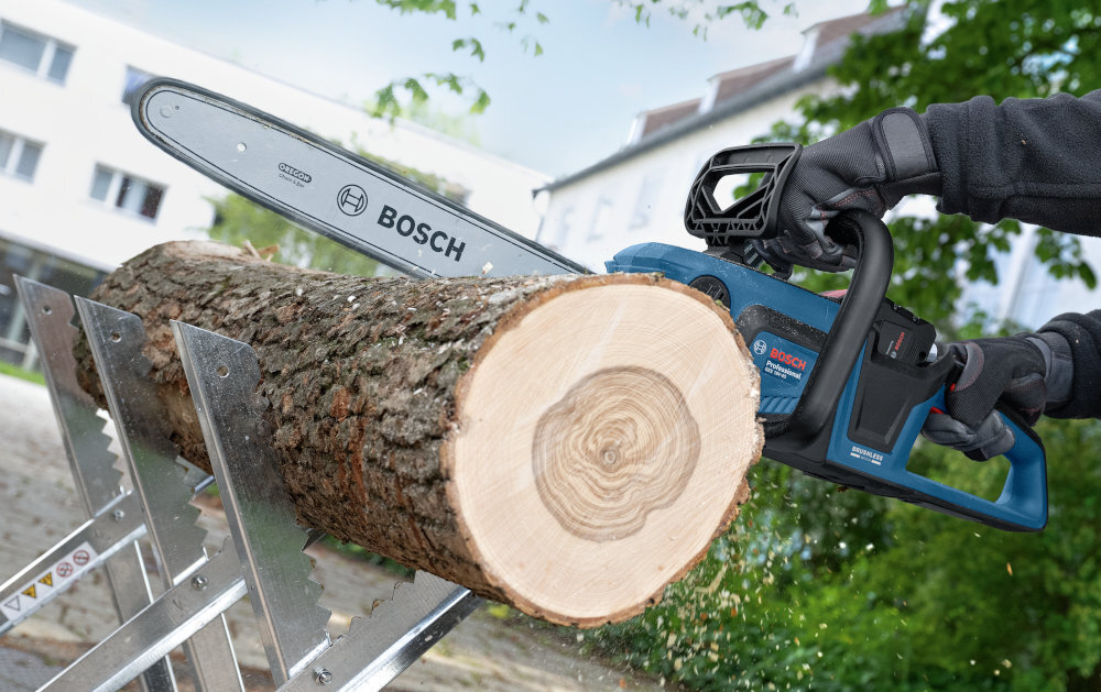 Piła akumulatorowa BOSCH Professional GKE 18V-40 06008D3000 plac budowy osoba tnie kłodę drewna w tle budynki prowadnica o długości 40 cm wysokiej jakości łańcuch OREGON 0,325” (8,25 mm) precyzyjne cięcie drewna i gałęzi prędkość łańcucha do 12,4 m/s efektywność pracy