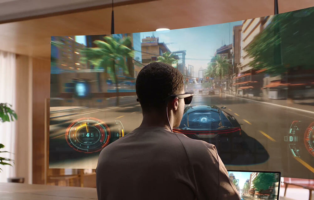 Okulary VITURE Pro XR Czarny prezentacja okularów podczas użytkowania mężczyzna w pokoju przed nim wirtualny obraz z gry samochodowej dźwięk przestrzenny HARMAN wciągające brzmienie odwrócone pole akustyczne dźwięk w wysokiej jakości