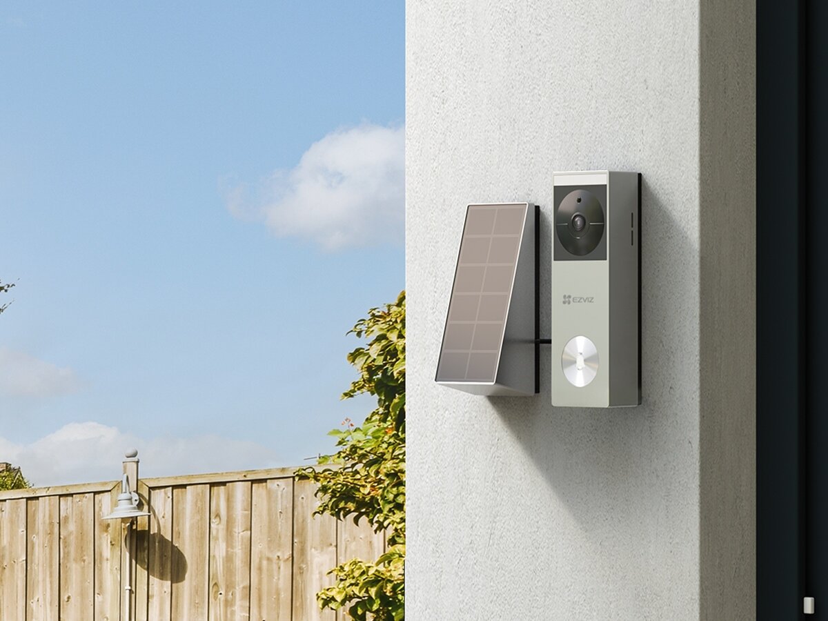 Wideodomofon EZVIZ CS-HP3 Pro Wi-Fi, szybki, montaż, ochrona, rozmowa, EZVIZ HP3 Pro z panelem słonecznym na elewacji, słoneczny dzień, drewniany płot w tle