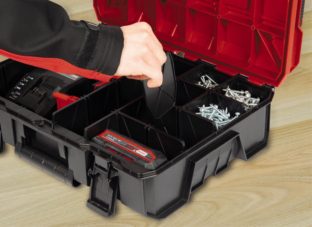 Walizka narzędziowa EINHELL E-Case S-F 4540020 otwarta skrzynka osoba trzyma jedną z przegródek w dłoni wnętrze walizki wypełnione narzędziami dwie długie trzy średniej długości cztery krótkie plastikowe przegródki segregowanie narzędzi i akcesoriów skraca czas poszukiwania potrzebnych części minimalizuje ryzyko uszkodzeń wspiera organizację pracy