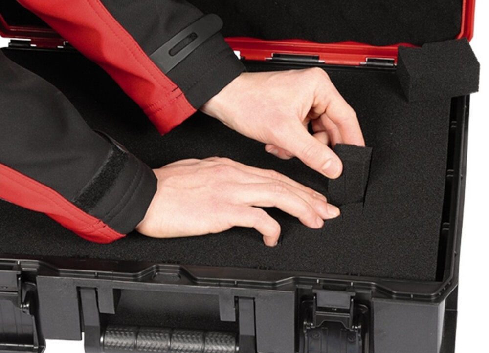 Walizka narzędziowa EINHELL E-Case S-F 4540019 otwarta skrzynka osoba ma dłonie oparte o piankę system dwóch piankowych wkładek sprzęt nie przesuwa się nie ulega zarysowaniom składane ergonomiczne uchwyty obciążenie do 25 kg