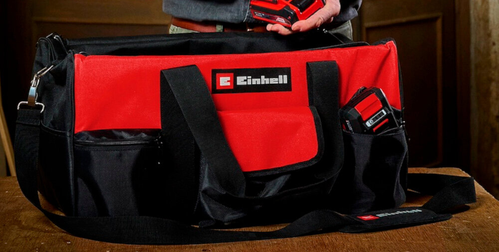 Torba narzędziowa EINHELL 4530078 pomieszczenie torba ustawiona na drewnianym stole w tle stoi osoba waga około 2,04 kg przemyślana konstrukcja komfort przenoszenia organizacja sprzętu