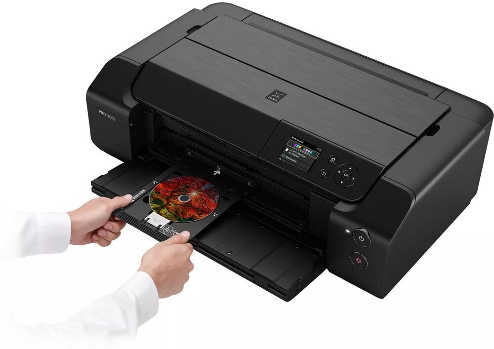 Drukarka CANON Pixma Pro-200S Druk w kolorze, Wi-Fi urządzenie na białym tle od przodu pod kątem dłonie trzymające tackę na płytę CD oprogramowanie Professional Print & Layout ułatwienie przygotowania plików programy Adobe podgląd efektów przed drukiem