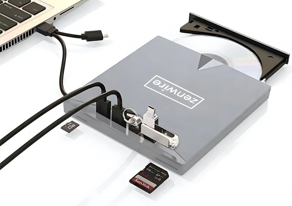 Napęd ZENWIRE H61 Srebrny napęd zewnętrzny podłączony do laptopa, z wysuniętą tacką, w której znajduje się płyta CD/DVD. Do urządzenia podłączone są różne akcesoria, w tym pendrive i czytnik kart pamięci, opis