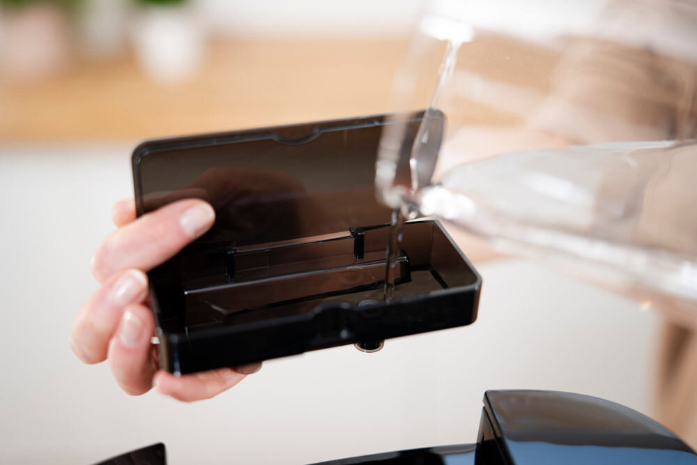 Air Fryer Frytkownica beztłuszczowa ZELMER ZAF8650 osoba wlewa do zbiornika wodę Steam Expert Technology równowaga chrupkość soczystość potraw precyzyjne wykorzystanie pary wodnej równomierne dopieczenie zachowanie wilgotności pełnia smaku dla miłośników kuchni smaczne zdrowe potrawy