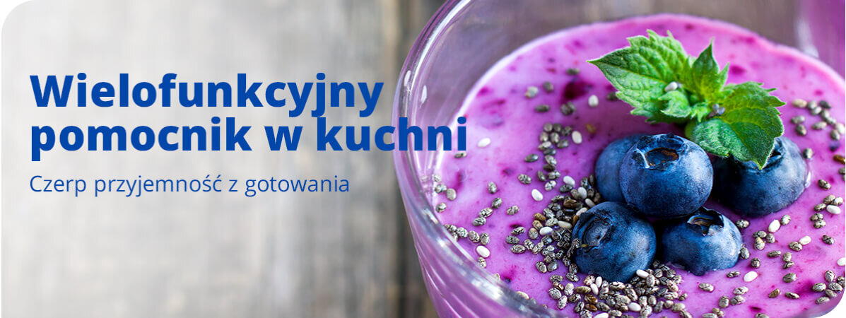 Na obrazie widoczny jest szklany kielich z fioletowym smoothie, udekorowanym jagodami, nasionami chia i listkiem mięty. Obok znajduje się tekst: \'Wielofunkcyjny pomocnik w kuchni. Czerp przyjemność z gotowania\'.