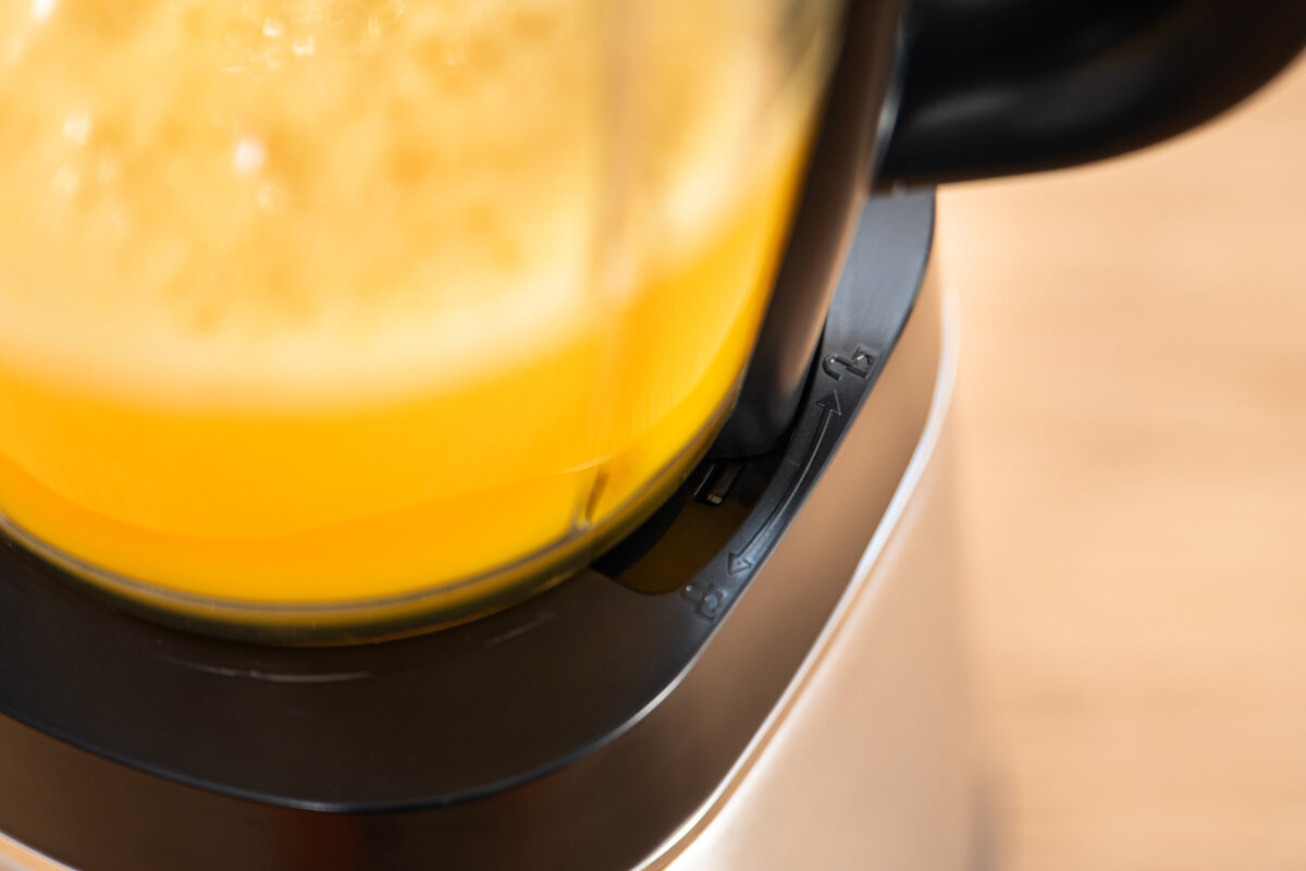 Zbliżenie na blender kielichowy z widocznym żółtym płynem w środku. Obudowa blendera jest srebrno-czarna.