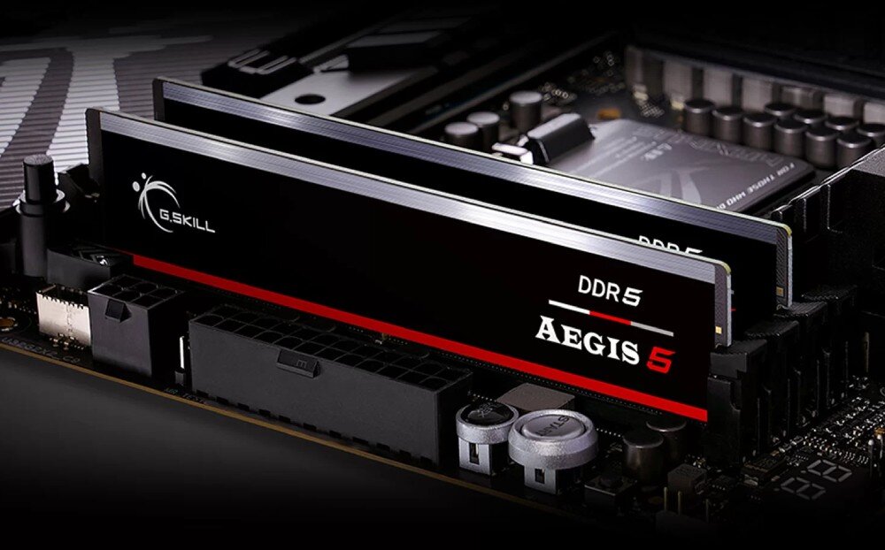Na obrazie widoczne są dwa moduły pamięci RAM z logo G.SKILL oraz napisami DDR5 i AEGIS 5, zamontowane na płycie głównej.