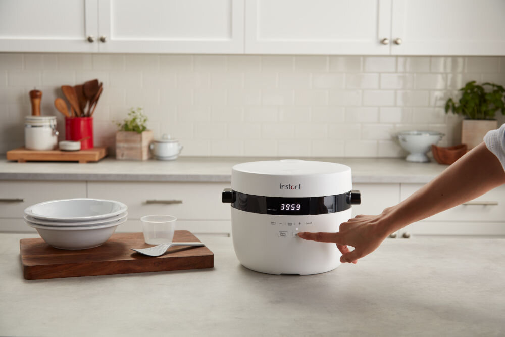 Ryżowar INSTANT POT Multigrain jasne tło kuchenne ryżowar w kolorze białym ręka naciskająca przycisk szereg funkcji łatwe i różnorodne gotowanie tryb powolnego gotowania (slow cook) długie gotowanie w niskiej temperaturze funkcja smażenia (sauté) podsmażanie składników gotowanie ryżu przygotowywanie innych dań
