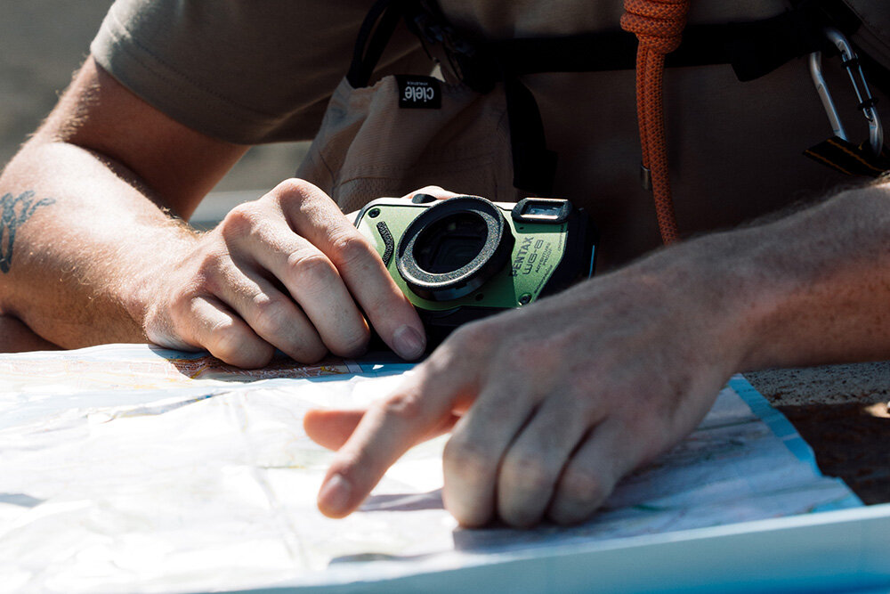 Aparat PENTAX WG-8 trzymany w dłoni podzczas korzystania z papierowej mapy