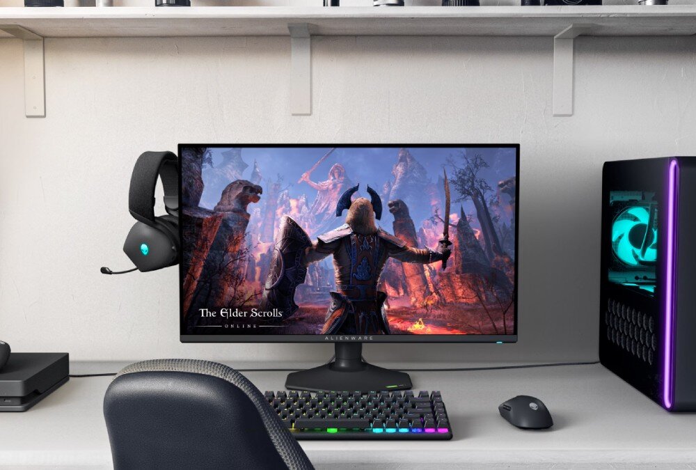 Monitor DELL Alienware AW2725QF Monitor na biurku z włączoną grą 'The Elder Scrolls Online', zestawem słuchawkowym zawieszonym z boku ekranu i komputerem stacjonarnym z podświetleniem RGB po prawej stronie, opis