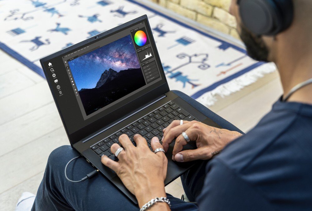 Dysk SANDISK Extreme Osoba siedzi z laptopem na kolanach i pracuje w programie do edycji zdjęć, na ekranie widoczna fotografia gór nocą, cechy, interfejs, technologia NVMe, prędkość odczytu