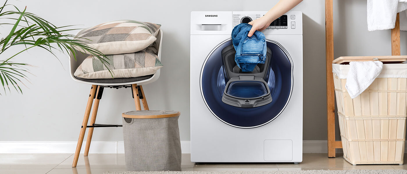 Zdjęcie użytkownika wkładającego jeansy do pralko-suszarki WD8NK52E0ZW przez dodatkowe drzwi AddWash™. Urządzenie dostępne jest w ofercie Media Expert