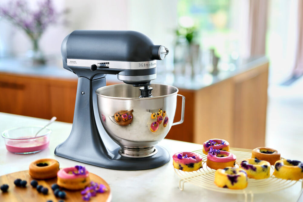 Robot kuchenny planetarny KITCHENAID Artisan 5KSM95PSEBS 275W kuchenny kompan robot niebieska obudowa suwak srebrna misa robot stoi na blacie obok słodkości na kratce