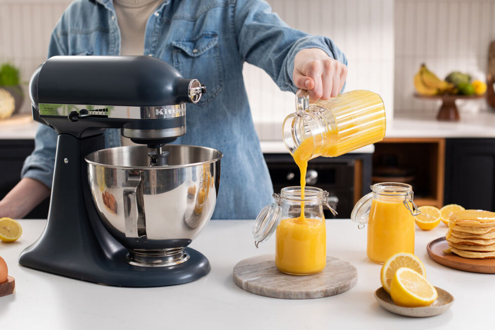 Robot kuchenny planetarny KITCHENAID Artisan 5KSM95PSEBS 275W niebieski robot srebrne misa suwak na obudowie osoba przelewa pomarańczową masę do słoika silnik o mocy 275 W konstrukcja bezpośredniego przeniesienia napędu małe i duże ilości składników Unikalny ruch planetarny mieszadła do kremów ciast ubijania piany precyzja wydajność