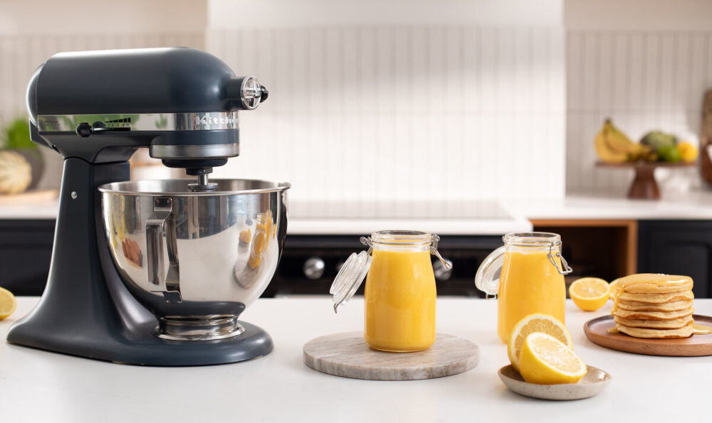 Robot kuchenny planetarny KITCHENAID Artisan 5KSM95PSEBS 275W niebieski robot srebrna misa suwak na obudowie pomarańczowa masa w słoikach w każdej kuchni osłona misy z przezroczystego tworzywa sztucznego wygodne dodawanie składników praktyczne rozwiązanie proste i przyjemne przygotowywanie potraw