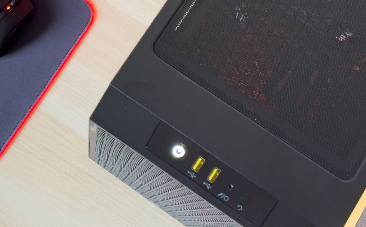 Komputer OPTIMUS E-Sport GA520T-CR5 Zbliżenie na górny panel obudowy komputera z przyciskiem zasilania, dwoma żółtymi portami USB, gniazdem słuchawkowym i siatką wentylacyjną, porty, gniazda, podłączenie