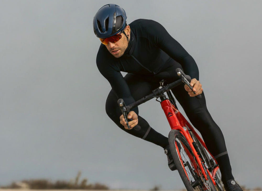 Kolarz szosowy w pochylonej pozycji aerodynamicznej na czerwonym rowerze, mający na sobie kask Lazer Vento.