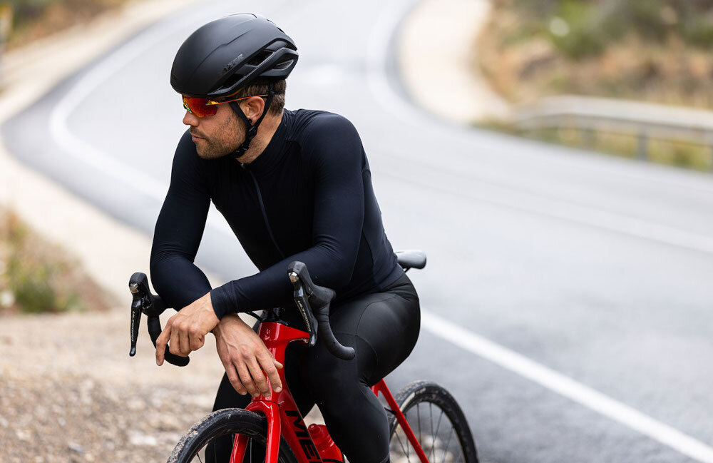 Kask rowerowy LAZER Strada KinetiCore Czarny Szosowy (rozmiar S) osoba w kasku siedzi na rowerze patrzy w dal w tle ulica miejsce na kucyk dopasowanie osobom z dłuższymi włosami wygoda bezpieczeństwo