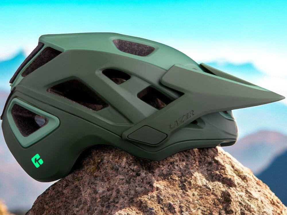 Kask rowerowy LAZER Jackal KinetiCore Zielony MTB (rozmiar S) osoba w założonym kasku na rowerze w górach