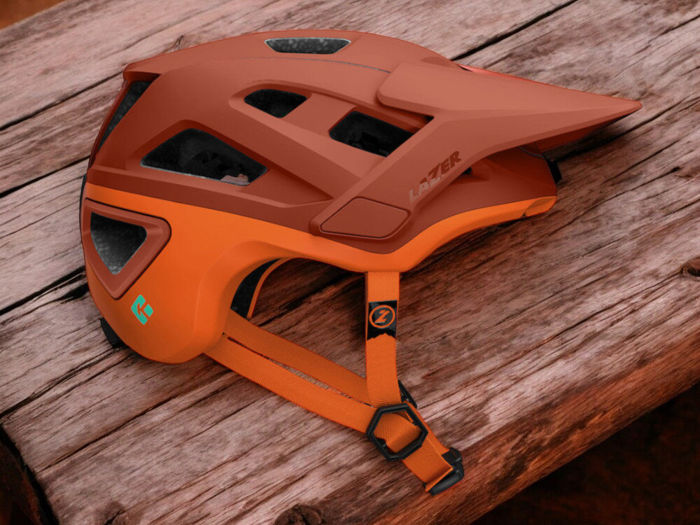 Kask rowerowy LAZER Jackal KinetiCore Pomarańczowy MTB (rozmiar L) osoba w założonym kasku na rowerze w górach