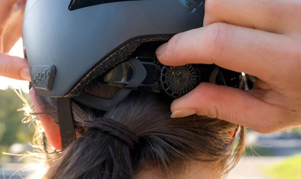 Kask rowerowy LAZER Maze KinetiCore Czarny Miejski(rozmiar S/M) osoba w kasku widoczna od tyłu w palcach trzyma pokrętło regulacyjne kask w rozmiarze S/M system Advanced TurnSys precyzyjna regulacja obwodu w zakresie 50-56 cm możliwość regulacji w pionie intuicyjne pokrętło stabilne dopasowanie utrzymuje kask we właściwej pozycji