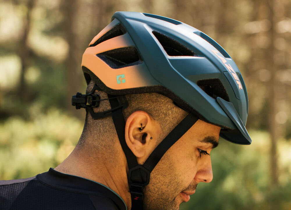 Kask rowerowy LAZER Cerro KinetiCore Niebiesko-pomarańczowy MTB (rozmiar L) osoba w kasku regulująca obwód kasku