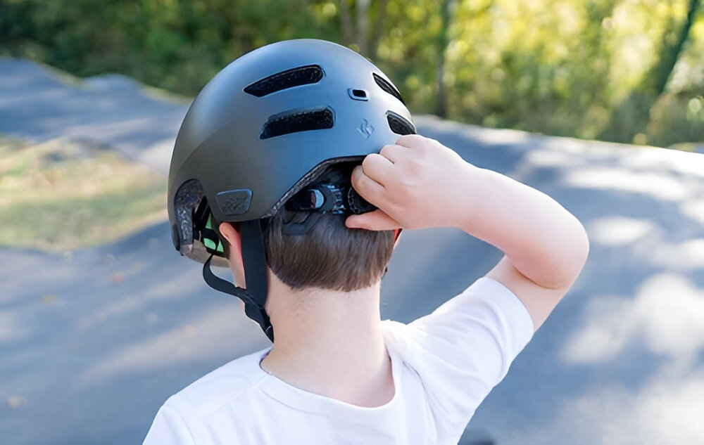 Kask rowerowy LAZER Maze Jr KinetiCore Czerwony dla Dzieci(rozmiar S/M) dziecko w kasku widoczne od tyłu w palcach trzyma pokrętło regulacyjne kask w rozmiarze S/M system Advanced TurnSys precyzyjna regulacja obwodu w zakresie 50–56 cm możliwość regulacji w pionie intuicyjne pokrętło stabilne dopasowanie utrzymuje kask we właściwej pozycji