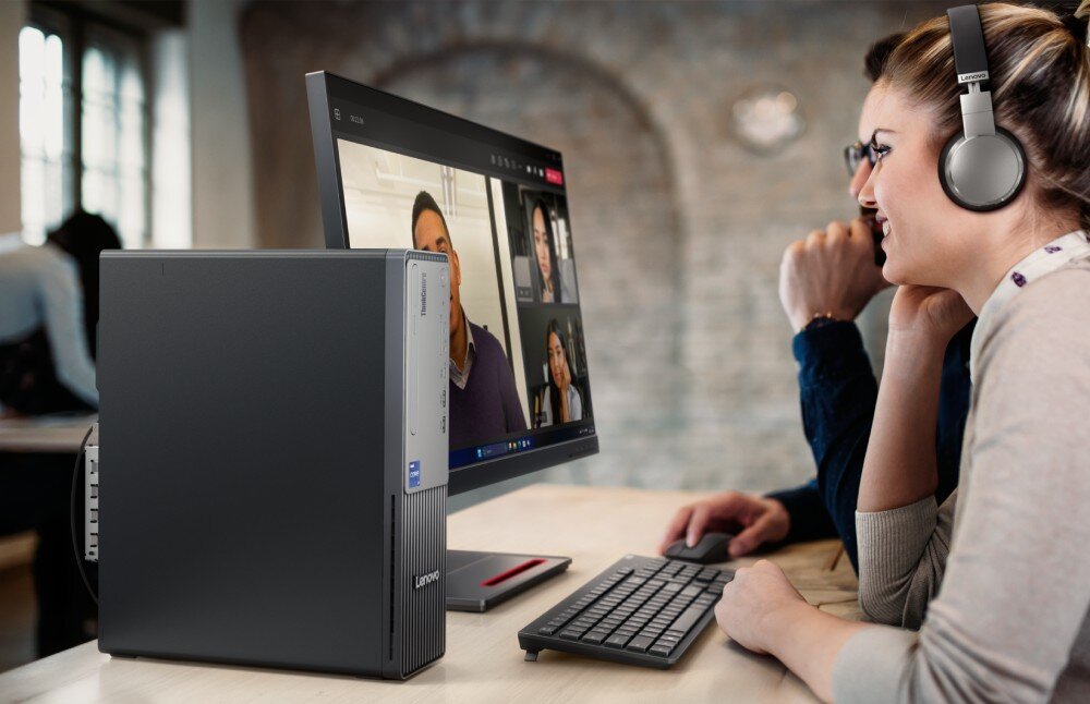 Komputer LENOVO ThinkCentre Neo 50s Gen 5 Osoba pisze na klawiaturze przy biurku, na którym stoi monitor wyświetlający okno czatu technicznego Lenovo AI Now oraz pionowa obudowa komputera typu SFF, opis