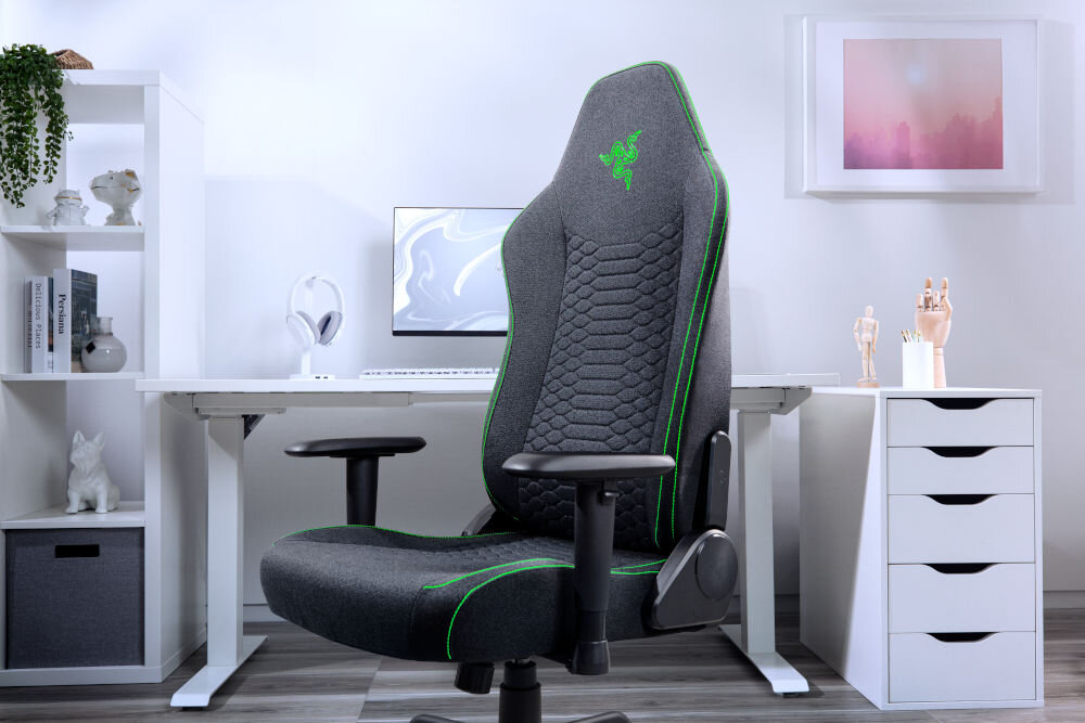 Fotel RAZER Iskur V2 X Czarny prezentacja fotela w jasnym pomieszczeniu biurowym w tle biurko komputer szafka pianki o dużej gęstości dopasowują się do kształtu ciała wspierają dolne partie utrzymanie stabilnej pozycji sprzyja wygodzie