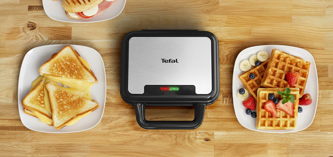 Opiekacz Ultra Compact SW383D 3W1 na kuchennym blacie, obok talerz z tostami i goframi.