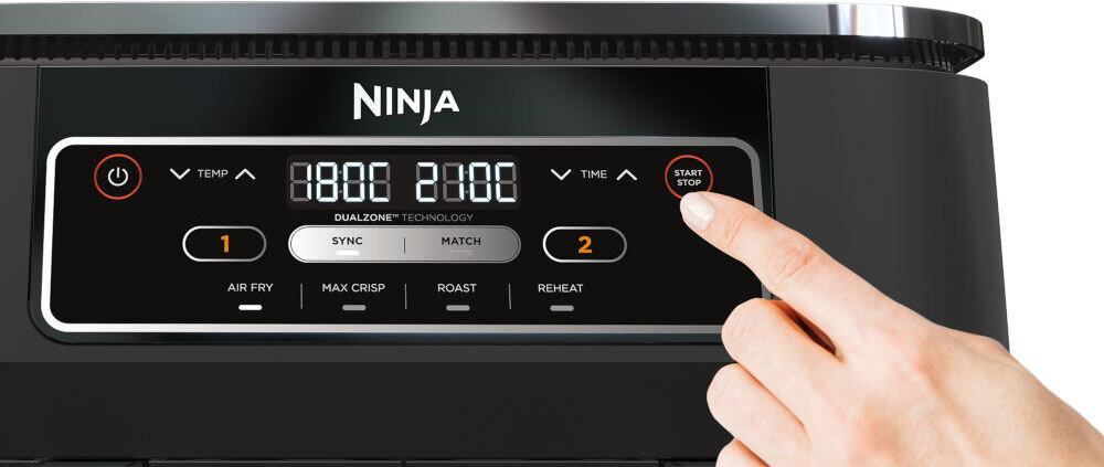 Air Fryer Frytkownica beztłuszczowa NINJA AF200EU z podwójnym koszem przybliżenie na panel sterowania palec przyciskający guzik wyświetlacz czarna obudowa białe tło 4 automatyczne programy pracy pełna kontrola precyzyjne monitorowanie czasu temperatury prędkości wiatraków prosty cyfrowy panel sterowania z minutnikiem zaprogramowanie każdej szuflady jeden palec kilka przycisków na urządzeniu