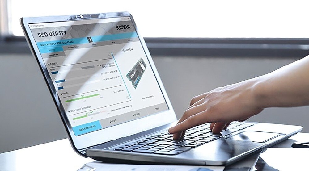 Dysk KIOXIA Exceria Plus G4 Laptop z uruchomionym oprogramowaniem SSD Utility oraz ręką osoby korzystającej z klawiatury, oprogramowanie, funkcje, narzędzia