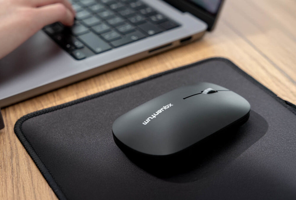 Mysz XQUANTUM WM400K leżąca na biurku na czarnej podkładce cicha praca