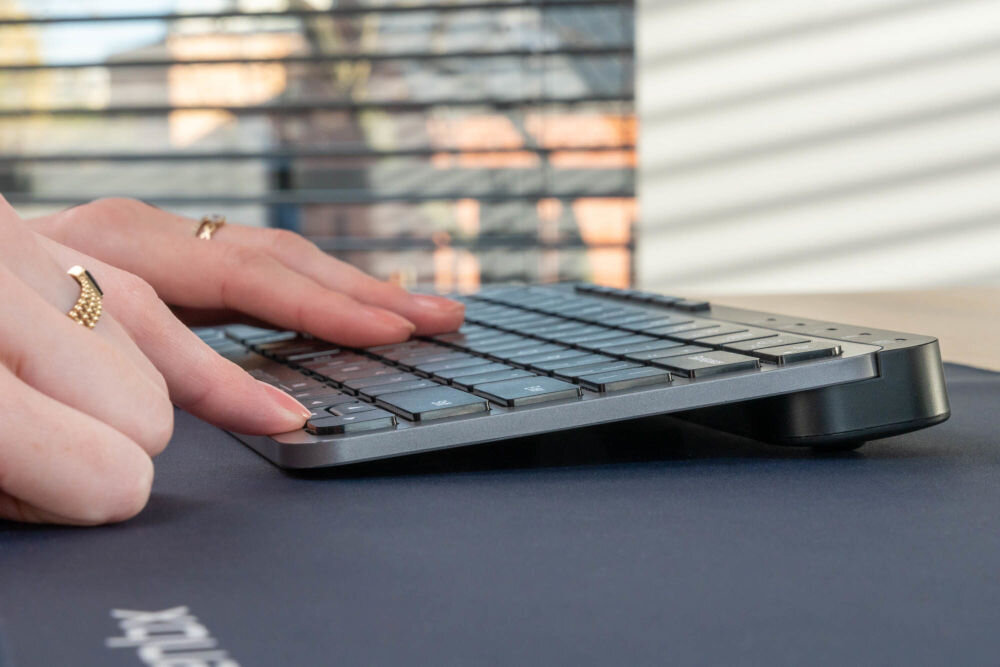 Klawiatura XQUANTUM WK510K Wireless pokazanie klawiatury w perspektywie od boku dłonie na klawiaturze niskoprofilowa konstrukcja klawisze nożycowe 84 klawiszy QWERTY bez bloku numerycznego oszczędność miejsca