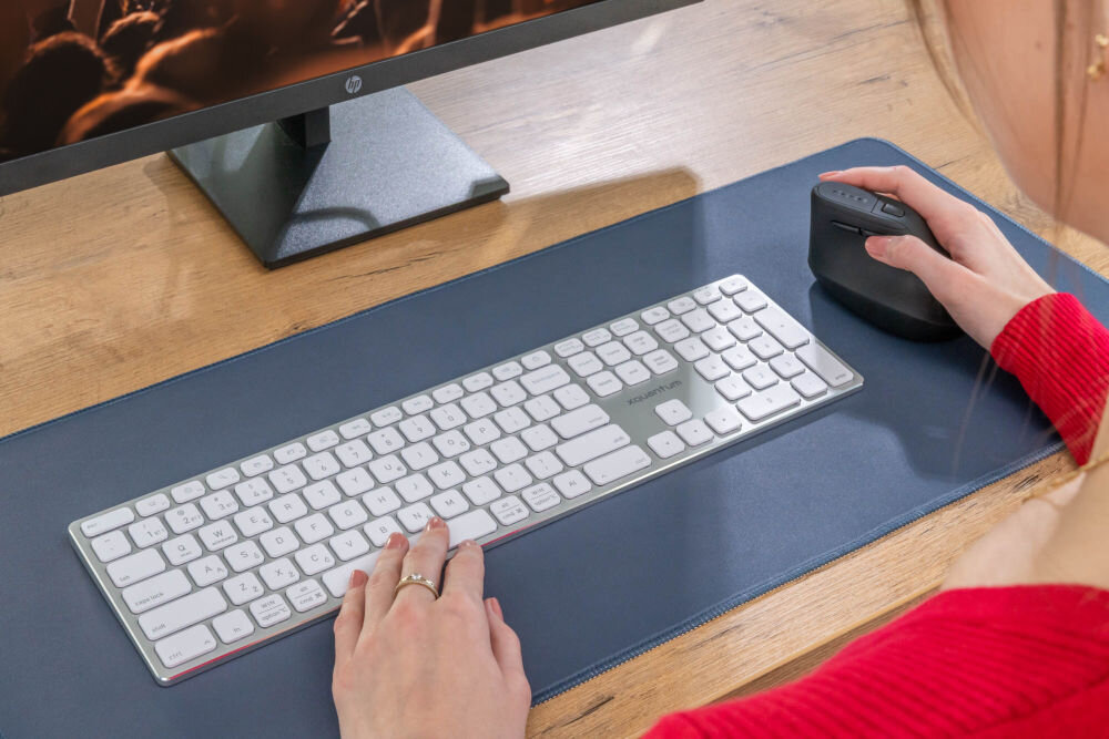 Mysz XQUANTUM WM700K Kobieta używająca myszy pionowej XQUANTUM WM700K przy biurku z monitorem i białą klawiaturą bezprzewodową.