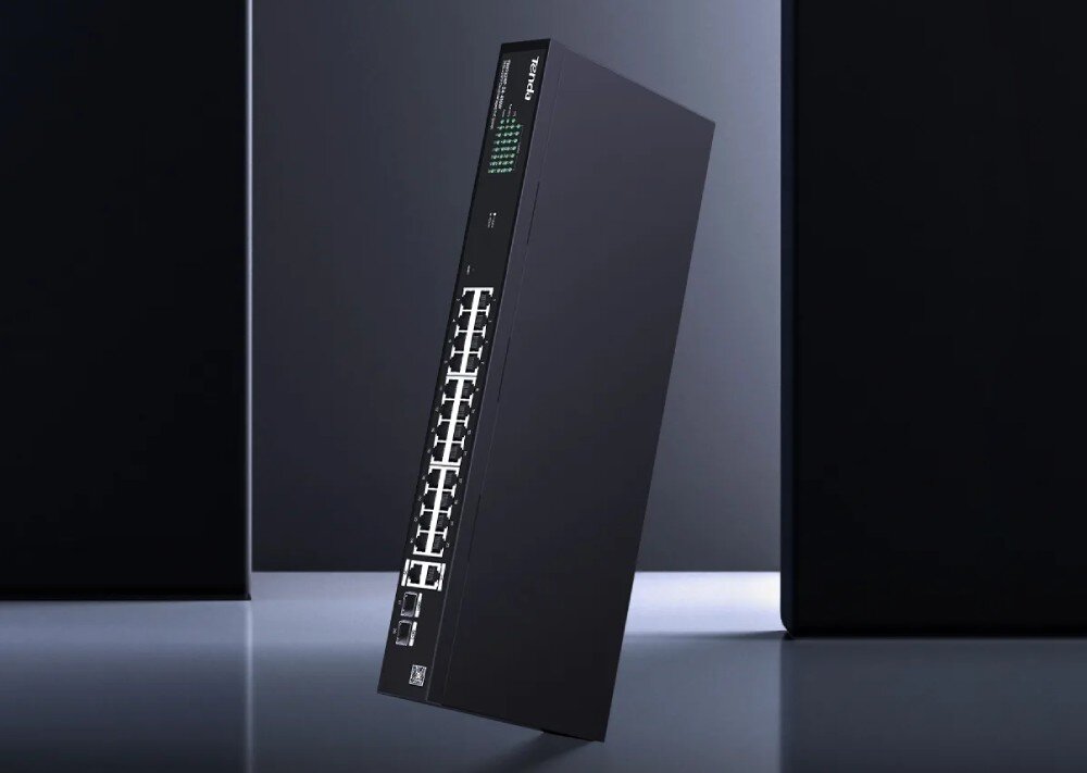 Na obrazie widoczny jest czarny switch sieciowy z 28 portami, z logo \'tenda\' na górze. Urządzenie jest ustawione pod kątem, a na jego powierzchni widać zielone diody sygnalizacyjne.