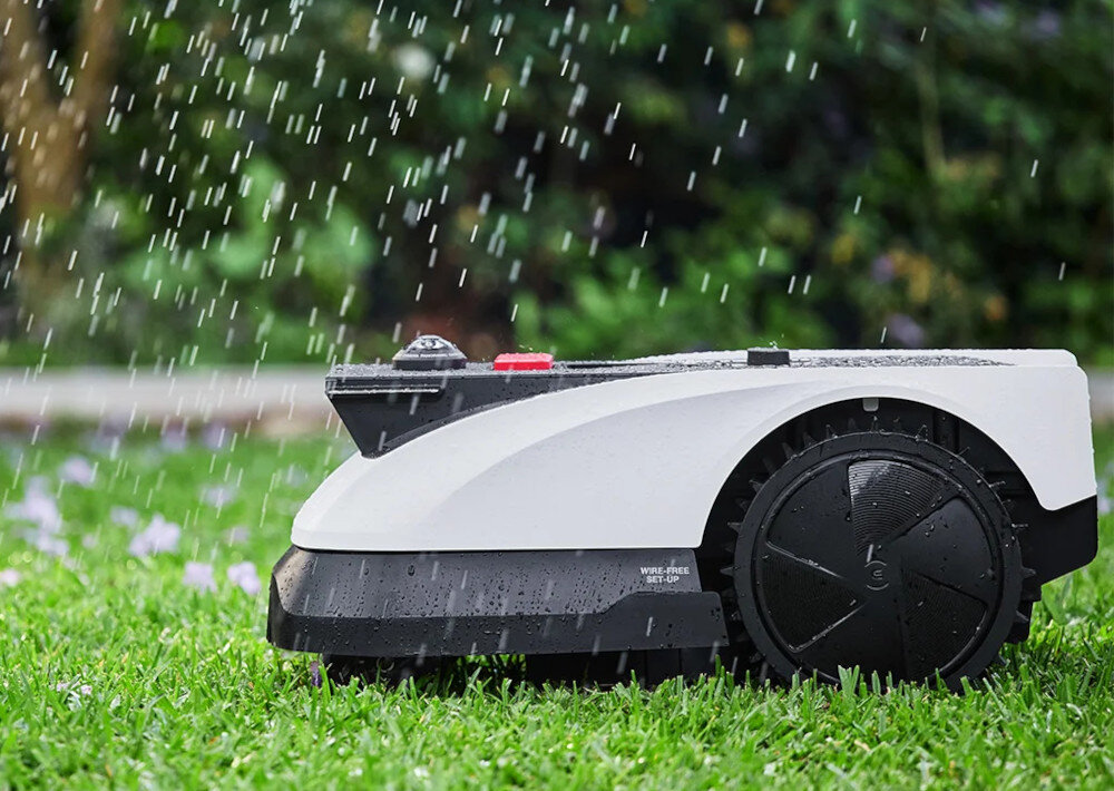 Robot koszący ECOVACS Goat O500 Panorama sterowanie Bluetooth-Wi-Fi robot stoi na trawie w strugach deszczu klasa szczelności IPX6 odporność na deszcz i trudne warunki pogodowe solidna konstrukcja proste czyszczenie płukanie wodą