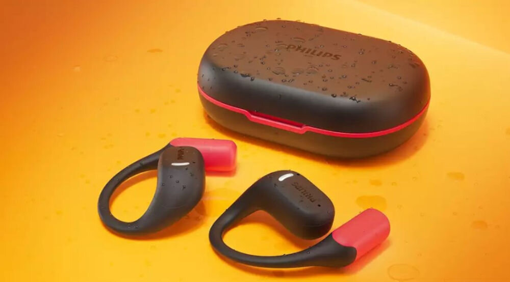 Słuchawki powietrzne PHILIPS TAA6709BK/00 odporność IP55 sport deszcz kurz światło do biegania, etui ładujące z słuchawkami powietrznymi w kroplach wody na pomarańczowym podłożu