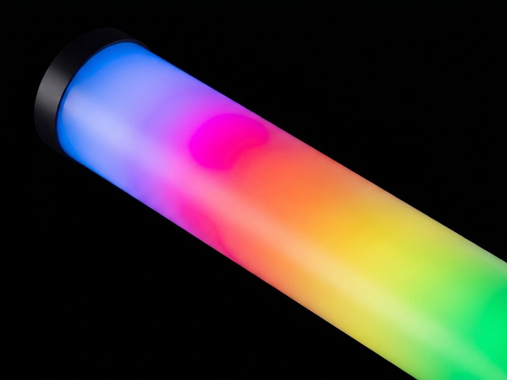 Lampa LED w kształcie tuby emituje wielokolorowe światło, przechodzące od niebieskiego przez różne odcienie czerwieni i żółci do zieleni. Tło jest czarne, co podkreśla intensywność kolorów lampy.