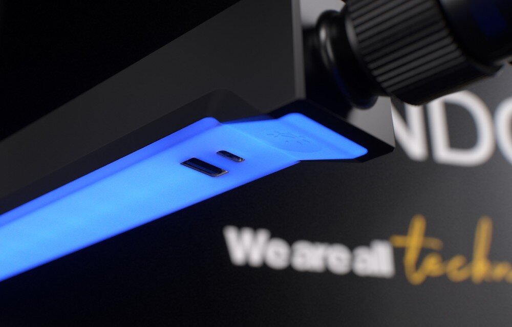 Ramię mikrofonowe ENDORFY Broadcast Low Profile RGB Boom Arm Zbliżenie na końcówkę ramienia z podświetleniem LED w kolorze niebieskim. W pobliżu znajdują się dwa porty: USB-A i USB-C, umożliwiające podłączenie urządzeń, zasilanie, gniazda