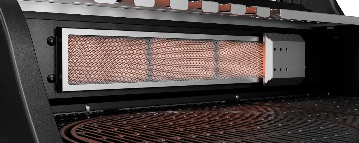 Obraz przedstawia wnętrze grilla gazowego z widocznym rusztem i elementem grzewczym. Element grzewczy ma metalową obudowę z siatką, przez którą prześwituje pomarańczowe światło.