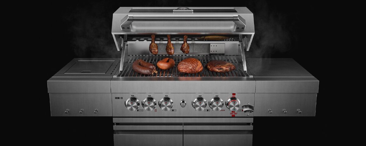 Duży grill gazowy z otwartą pokrywą, na ruszcie znajdują się różne rodzaje mięsa. Grill wykonany jest ze stali nierdzewnej i posiada kilka pokręteł do regulacji temperatury.